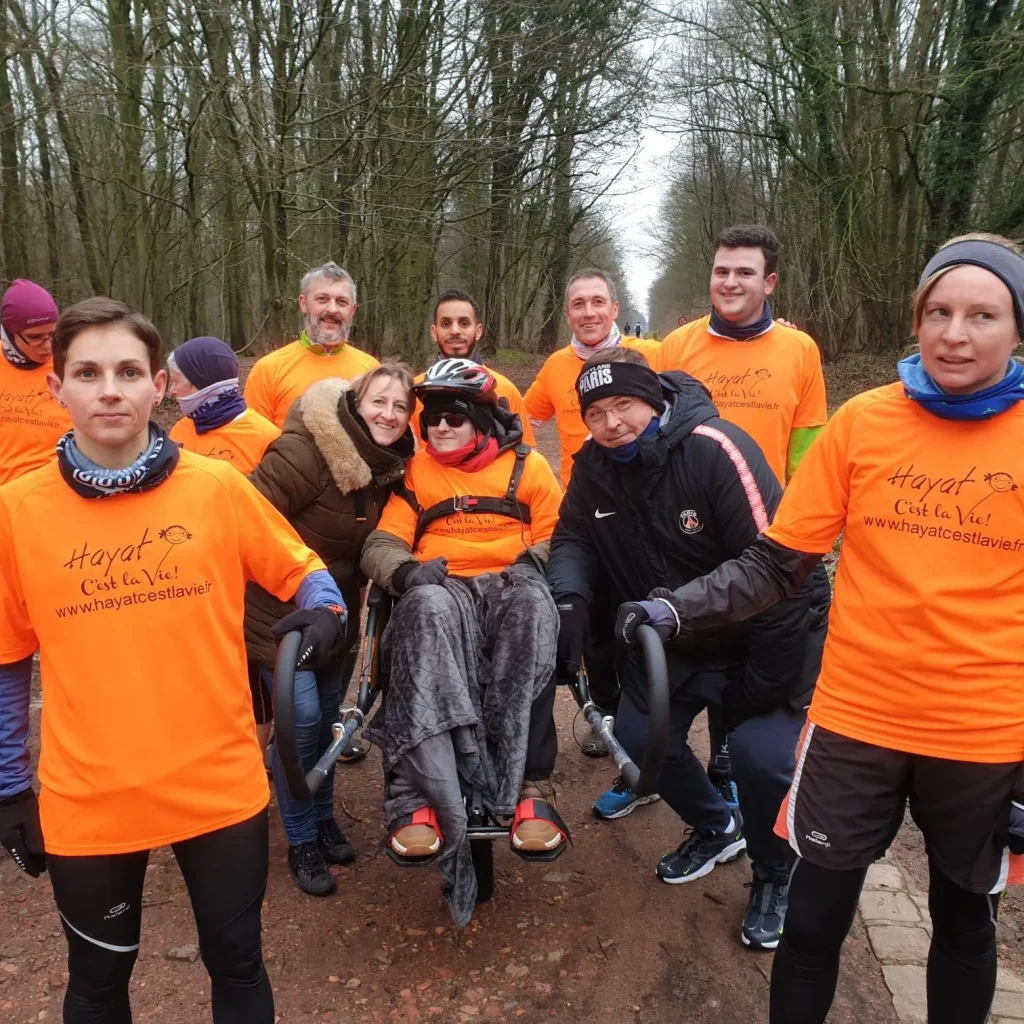 L'équipe Hayat c'est la vie en t-shirts orange autour d'une joëlette en forêt