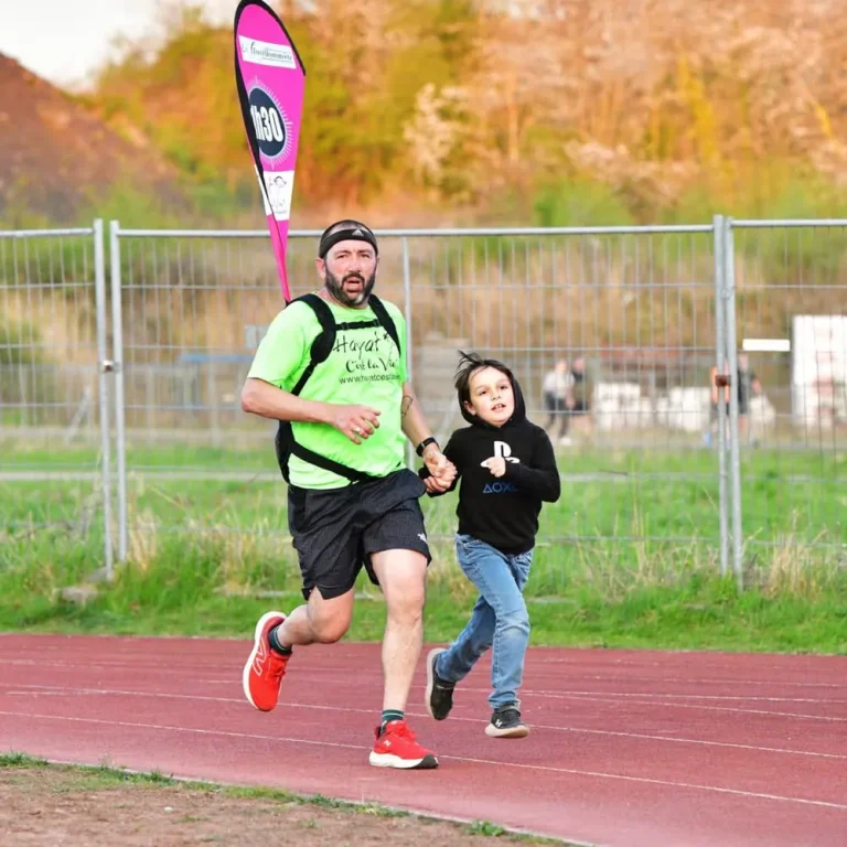 Un guide court en tenant la main d'un enfant sur une piste d'athlétisme