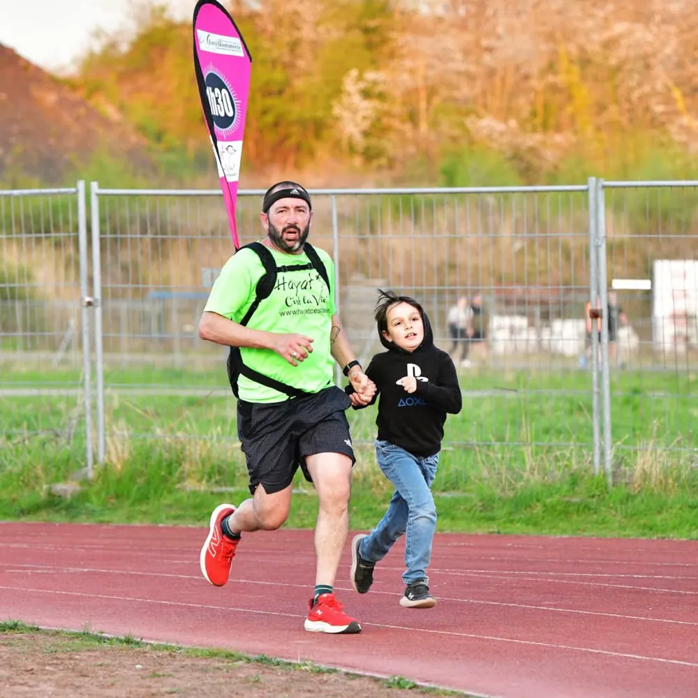 Un guide court en tenant la main d'un enfant sur une piste d'athlétisme