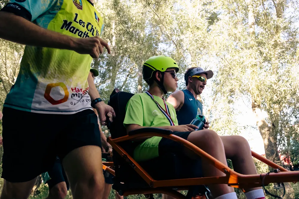 Un jeune pilote casqué en joëlette pendant une course solidaire